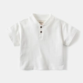 Close-up of boys' white polo shirt featuring a ribbed collar and brown wood-grain buttons - 90cm / White