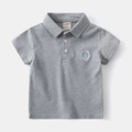 Detailaufnahme von grauem Kinder-Poloshirt-Kragen mit aufgesticktem Segelboot-Logo - 90cm / Grau