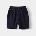 Close-up of boys navy casual shorts featuring elastic waist and metal button detail - Navy Blue / 90cm