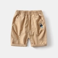 Dettaglio dei pantaloncini di cotone kaki con vita elastica e ricamo a forma di orso sulla tasca - 90cm / Cachi