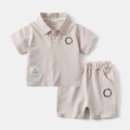 Dettaglio dell'insieme polo e pantaloncini beige in cotone per bambini con ricami - Cachi / 90cm