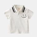 Dettaglio di polo bianca per bambini con colletto a righe e simpatica faccina - Bianco / Taglia 90