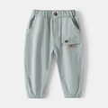 Close-up of child joggers featuring an elastic waistband with decorative button and side pocket - Size 110 / Bean Green