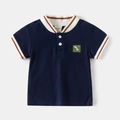 Detailansicht des dunkelblauen Poloshirts mit Dinosaurier-Stickerei und gestreiftem Kragen - 90cm / Marineblau