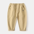 Dettaglio dei pantaloni kaki per bambini con ricamo di orsetto ed elastico in vita - 90cm / Cachi