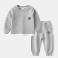 Detail van grijze sweatshirt en joggingbroek set voor kinderen met geborduurde badge - 120cm / Grijs