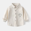 Detail of boys beige cotton shirt showing metallic buttons and cartoon chest pocket print - 100cm / Apricot