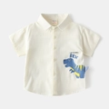 Dettaglio di una camicia da neonato color crema con stampa di dinosauro blu - Bianco / 90cm