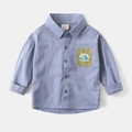 Détail d'une chemise bleu clair pour garçon avec écusson de dinosaure et étiquette de col - 90cm / Bleu Denim