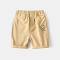 Detail of kids' khaki shorts featuring elastic waistband and small cartoon face embroidery - Khaki / 90cm