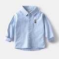 Dettaglio camicia oxford azzurra con ricamo a orsetto e bottoni bianchi da bambino - 90cm / Blu