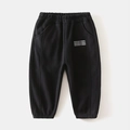Close-up of black fleece-lined boys' joggers with elastic waist and white lettering - 90cm / Black