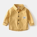 Detail of a bright yellow boy's cotton shirt featuring a chest pocket and text label - Yellow / 90cm