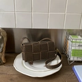 Detail of woven square crossbody bag with vintage monogram pattern on a white plate - Brown