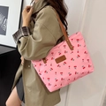 Pink cherry print tote bag with brown leather handles worn with a khaki coat - Pink