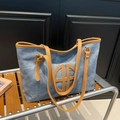 Blue denim tote bag with brown leather straps and circular geometric logo on black background - Blue Khaki