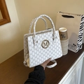 Elegante borsa bianca con stampa a lettere M e logo dorato su un tavolo di legno - Bianco
