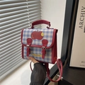 Mini zaino a quadretti blu con dettaglio mela rossa e spallacci in pelle in mano - Rosso