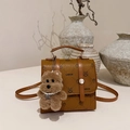 Brown leather crossbody bag with cartoon print and dog charm in elegant home setting - With Pendant / Brown