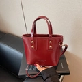 Bolso saco color burdeos en piel sintética brillante con tachuelas doradas y asas - Burdeos