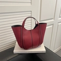 Chic red bucket bag with black contrast stitching on a minimalist white book pedestal - Red