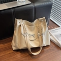 Minimalist beige tote bag with silver bow and chain strap on a wooden floor - Off-white