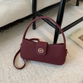 Elegante bolso baguette de ante burdeos con detalle de bocado dorado en alfombra blanca - Rojo