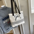 Detail of canvas tote bag with embroidered bow design and vertical striped pattern - White