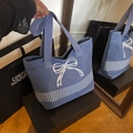 Close-up of blue canvas tote bag featuring large white bow embroidery and vertical stripes - Blue