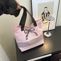 Detailed shot of pink canvas tote bag with black bow embroidery and dark brown straps - Pink