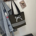 Close-up of green canvas tote bag featuring white bow embroidery and brown handles - Green