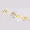 Close-up of white satin The Bride sash with gold glitter text and wedding icons - Satin Sash / White Gold Text-The Bride Ring Heart
