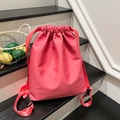 Mochila tipo cubo rosa con cordón y correas anchas sobre una escalera de madera interior - Rosa Rojo