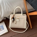 Détail du sac à main crème élégant avec texture tissée et breloque décorative en perles - Avec Pendentif / Blanc
