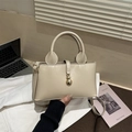 Detailed shot of beige leather tote bag with gold gourd-shaped lock on a desktop - Khaki