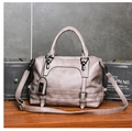 Detalle de bolso Boston topo con textura de cuero, hebillas de metal y colgante de marca - Gris