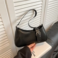 Sac baguette noir de style français avec boucle argentée tenu devant un décor moderne - Noir
