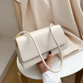Elegant cream rectangular shoulder bag with gold metal buckles on a white chair - White