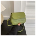 Close-up of avocado green saddle bag with crocodile texture and silver typography - Green