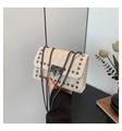 Chic beige woven crossbody bag with studs and chain strap shown in an elegant interior - Off-white