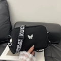 Black nylon crossbody bag with white butterfly charm and wide lettered strap - Black