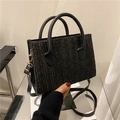 Detail of black woven crossbody bag with leather handles and gold metal hardware - Black