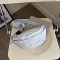 Light blue pleated fabric waist bag with adjustable strap on a beige leather seat - Blue