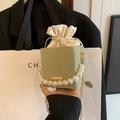 Light green bucket bag with large pearl handle and gold chain strap shown on black blazer - Green