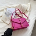 Sac à bandoulière rose en cuir PU avec détails dorés posé sur une veste beige - Rose Rouge