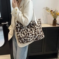 Borsa tote in peluche leopardata con tracolla bianca indossata da una modella in un set elegante - Bianco