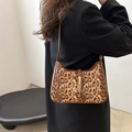 Borsa leopardata sottobraccio con fibbia dorata indossata da modella in cappotto - Marrone