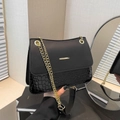 Chic black shoulder bag with crocodile pattern and golden chain strap in hand - Black
