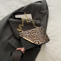 Chic leopard print and black leather crossbody bag with gold chain strap on grey blazer - Black