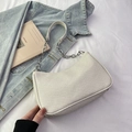 Bolso bajo el brazo tejido beige minimalista con cadena plateada sobre fondo de tela blanca - Blanco Roto